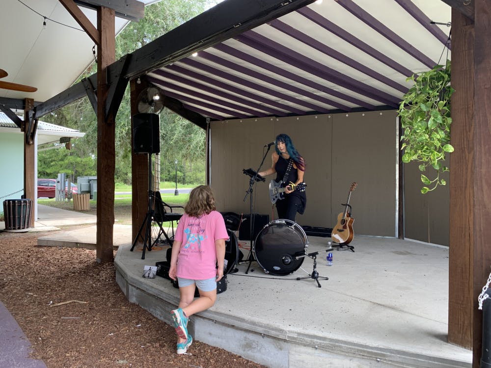 Musician Camie Maree plays on stage at One Love Cafe and interacts with a young fan. 