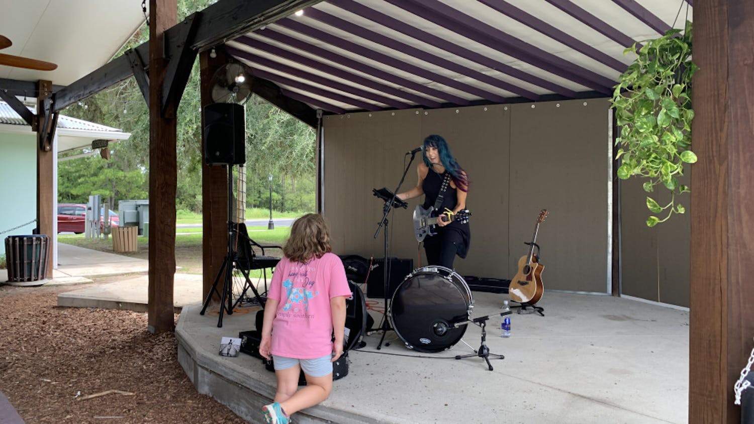 Musician Camie Maree plays on stage at One Love Cafe and interacts with a young fan.