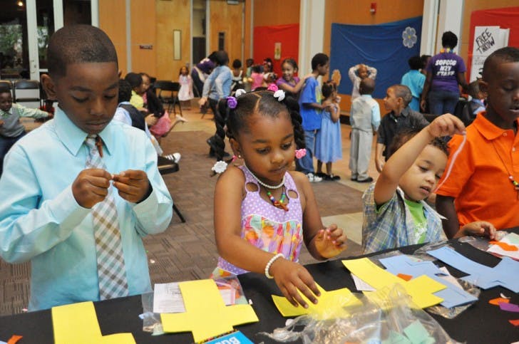 Rashid Latson, 6, Jalaya Husain, 4, Catrel Husain, 3, and Tyrin Williams, 7, make "stained glass" crosses out of foam and tissue paper at one of the activity tables for the Spirit of Faith Christian Center's children’s Easter service at the Phillips Center for the Performing Arts on Sunday.