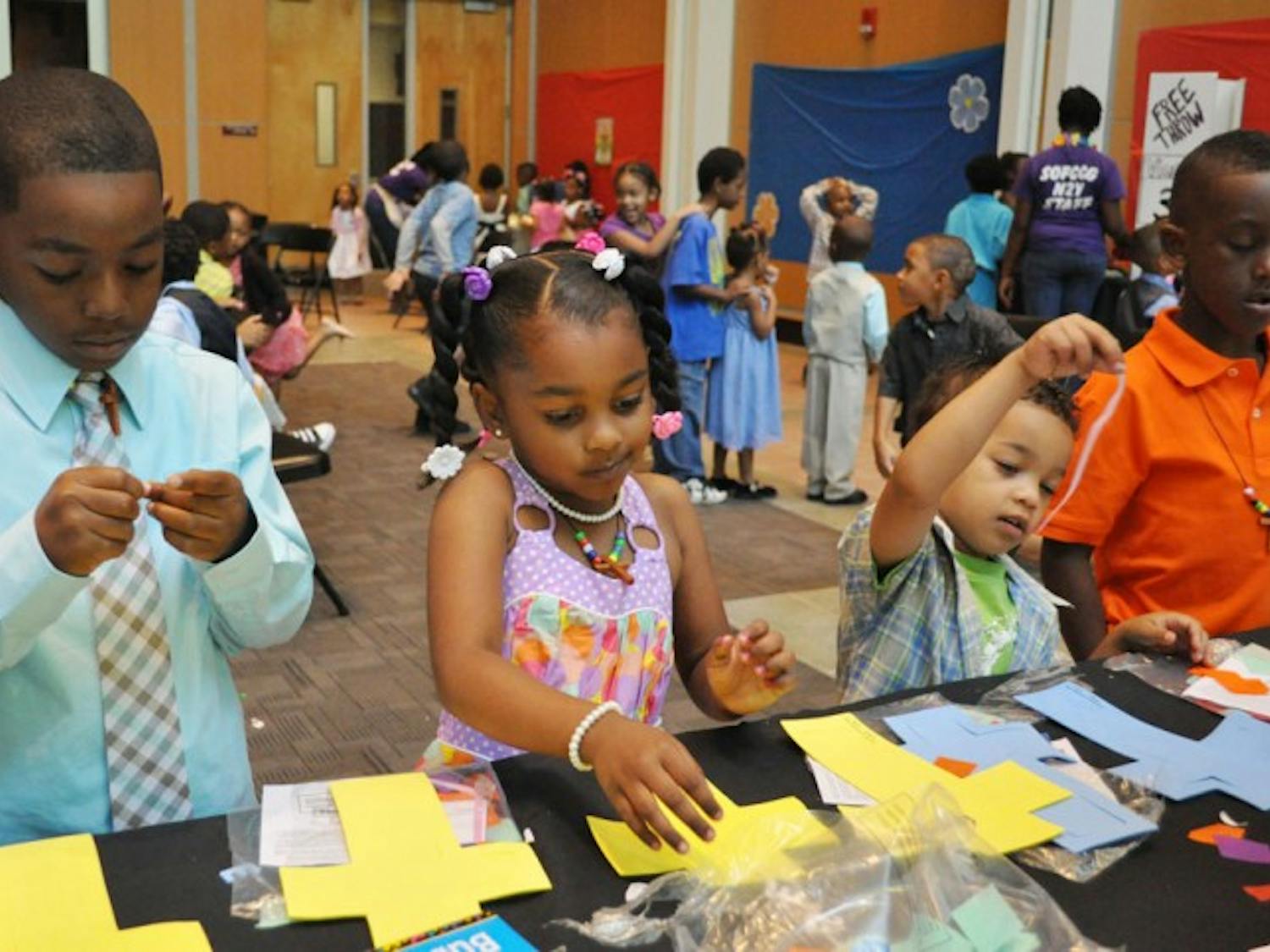 Rashid Latson, 6, Jalaya Husain, 4, Catrel Husain, 3, and Tyrin Williams, 7, make "stained glass" crosses out of foam and tissue paper at one of the activity tables for the Spirit of Faith Christian Center's children’s Easter service at the Phillips Center for the Performing Arts on Sunday.