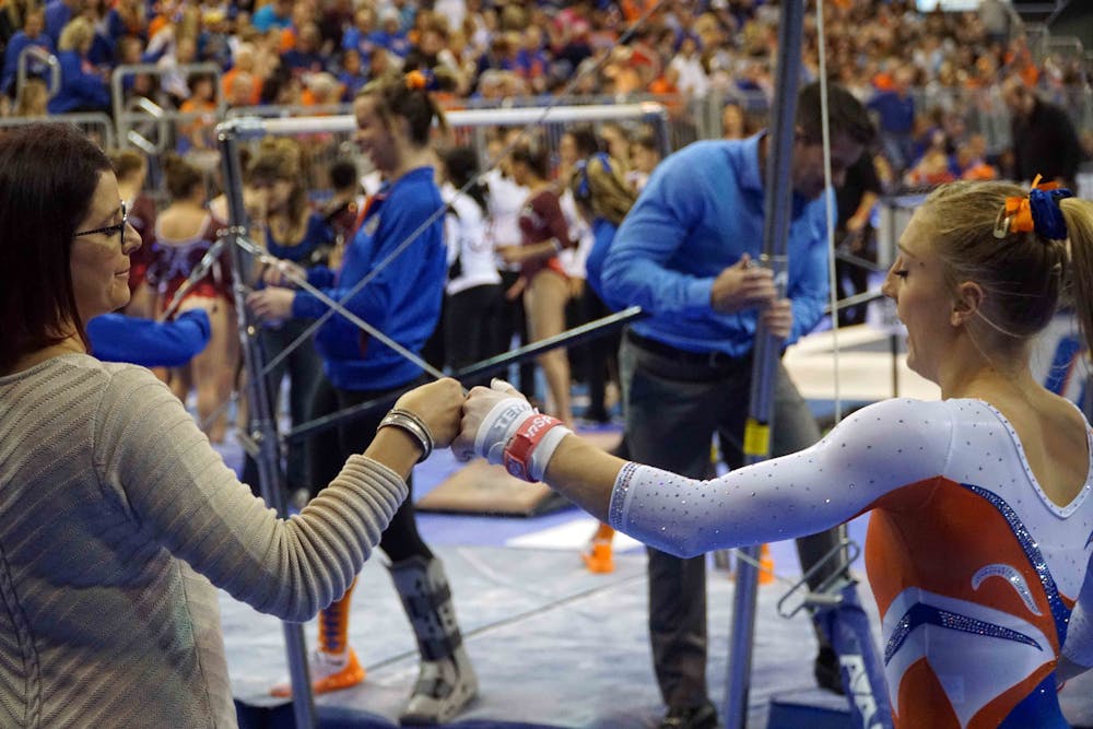 <p>Coach Jenny Rowland fist-bumps gymnast Alex McMurtry prior to McMurtry’s uneven parallel bars during Florida’s win against Alabama on Jan. 29, 2016, in the O’Connell Center.</p>