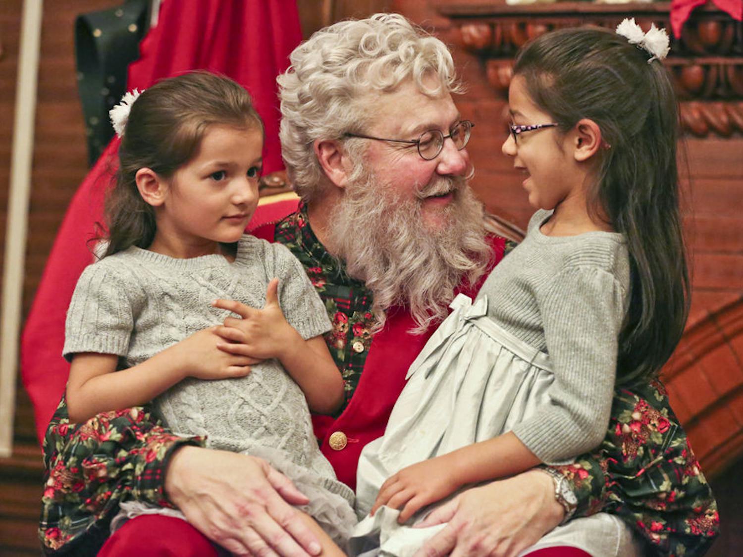 Four-year-old Olivia Wood, left, and 6-year-old Isabel Wood tell Santa about their Christmas wishes during the annual Holiday Tree Lighting ceremony on Saturday. “They’re always super excited for Christmas,” said Ligia Wood, a web designer and the girls’ mother.
