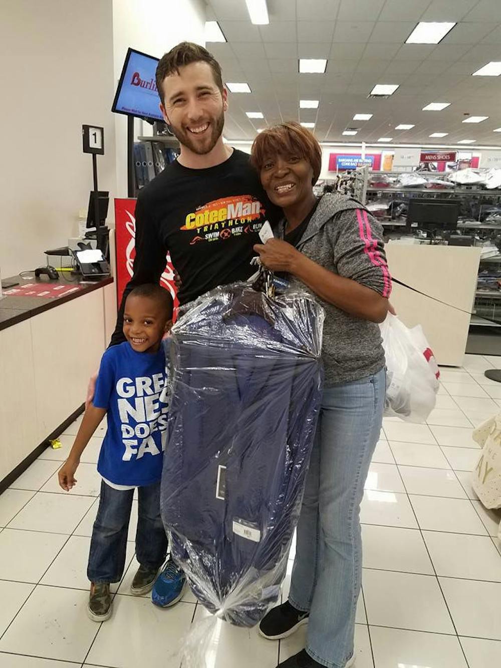 <p>Eric Gilbert, a co-founder of Remedium, poses with a Burlington Coat Factory customer and her son. Gilbert, 34, paid for a men’s suit the woman had on layaway — a Christmas present for her husband.</p>