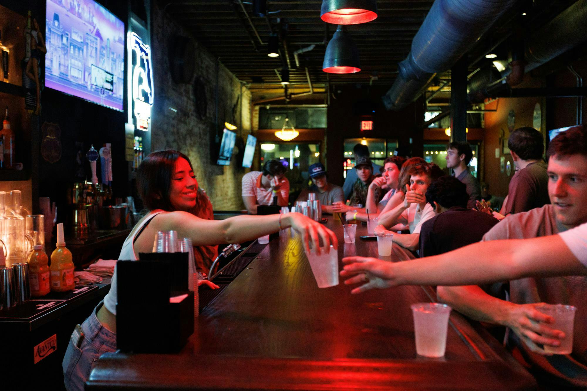 A bartender hands a drink to a patron at Whoopi's, Friday, March 6, 2026, in Gainesville, Fla.