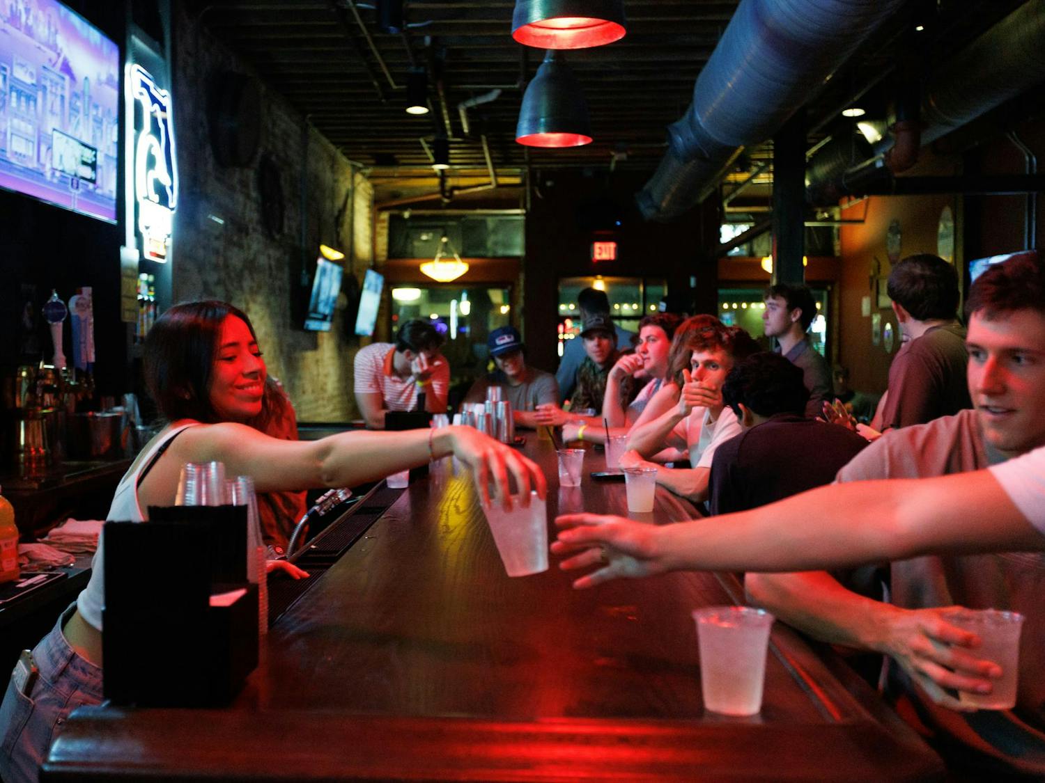 A bartender hands a drink to a patron at Whoopi's, Friday, March 6, 2026, in Gainesville, Fla.