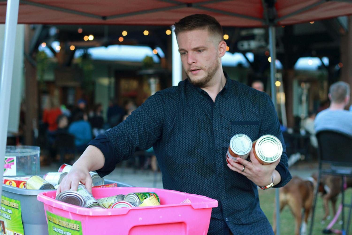 Fundraising organizer Andrew Poe, 28, consolidates donations of canned food Sunday at a food truck rally. Donated food will be given to Bread of the Mighty Food Bank.