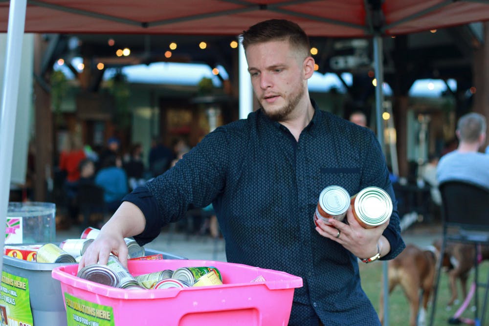 <p dir="ltr"><span>Fundraising organizer Andrew Poe, 28, consolidates donations of canned food Sunday at a food truck rally. Donated food will be given to Bread of the Mighty Food Bank.</span></p>