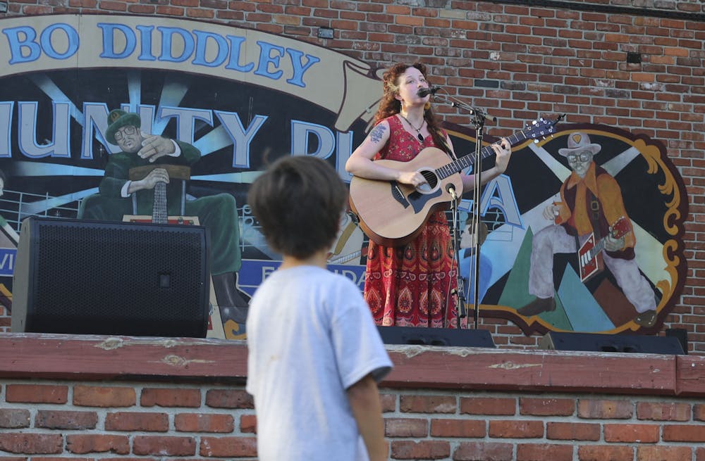 A boy look up at Sara Donnachie, also known as Pose Norma, a Santa Fe music theory student, singing on stage at Bo Diddley Plaza in Gainesville on Thursday, July 15, 2021.