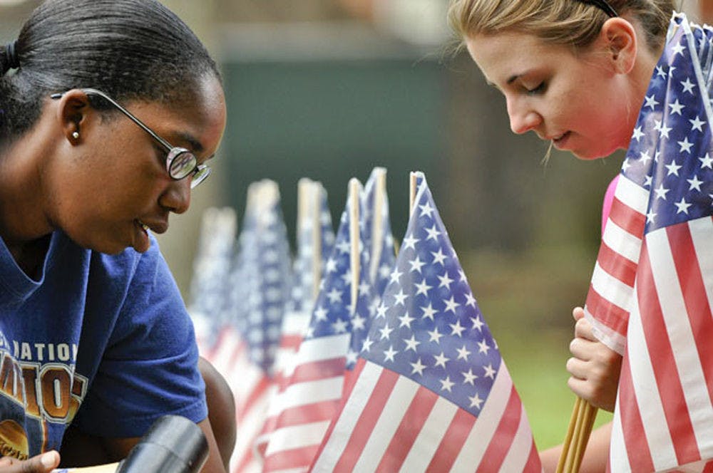 Natalie Ford and Jessica Gordon tap flags into the ground Sept. 6, 2010. The flags are part of a 9/11 memorial sponsored by College Republicans and Network of enlightened Women in the Plaza of the Americas.