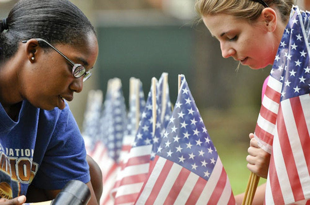 <p>Natalie Ford and Jessica Gordon tap flags into the ground Sept. 6, 2010. The flags are part of a 9/11 memorial sponsored by College Republicans and Network of enlightened Women in the Plaza of the Americas.</p>