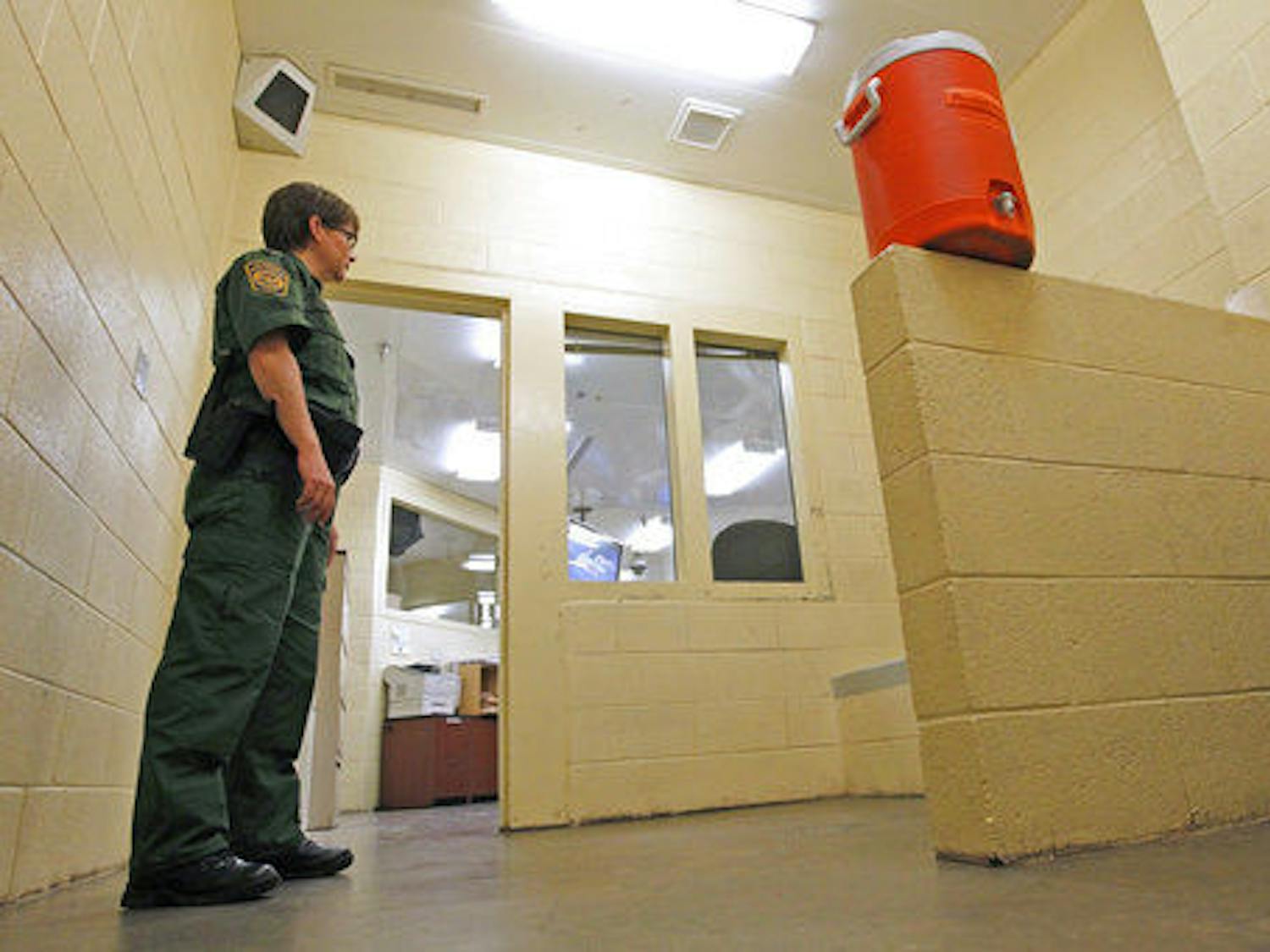In this Thursday, Aug. 9, 2012, file photo, a Border Patrol agent stands inside one of the holding areas at the Tucson Sector of the U.S. Customs and Border Protection headquarters in Tucson, Arizona.