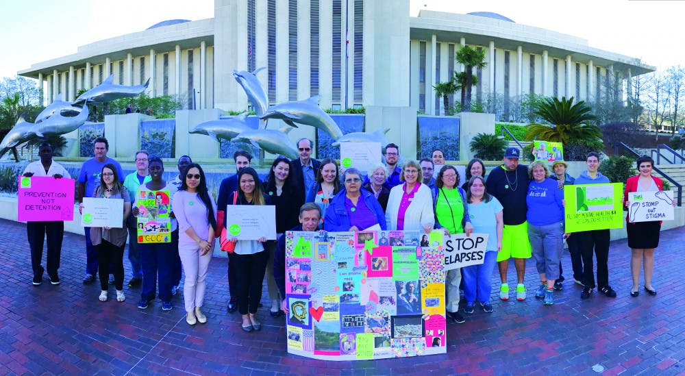 About 60 people pose for a photo in Tallahassee on Thursday. The group traveled to the state capitol to lobby for better mental health services in Florida. 