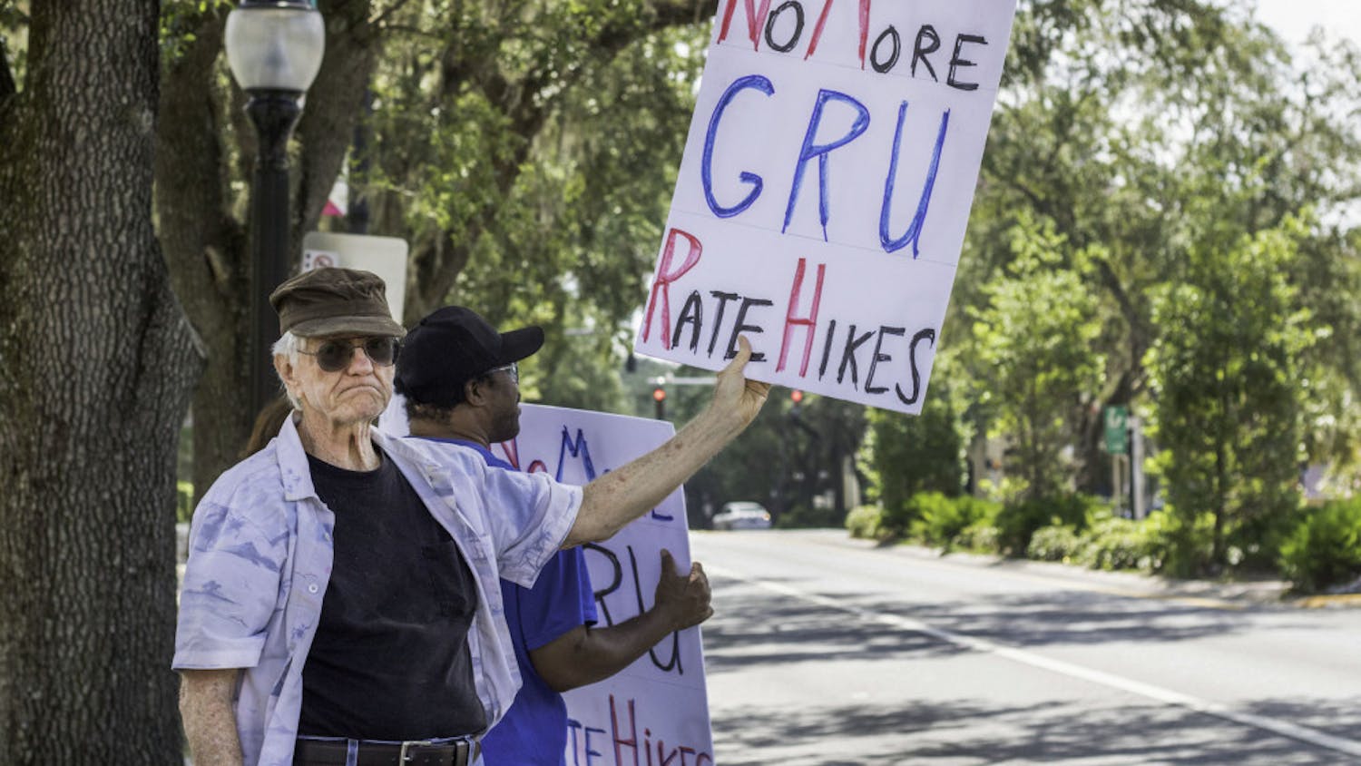 Harold Saive, 75, holds up a protest sign while Jason Davis, 46, stands behind him noon Thursday along University Avenue outside of City Hall. Saive said he believes that most people support the cause but are too timid to protest in person. “For every person who shows up here there’s a thousand behind them who agree,” Saive said.