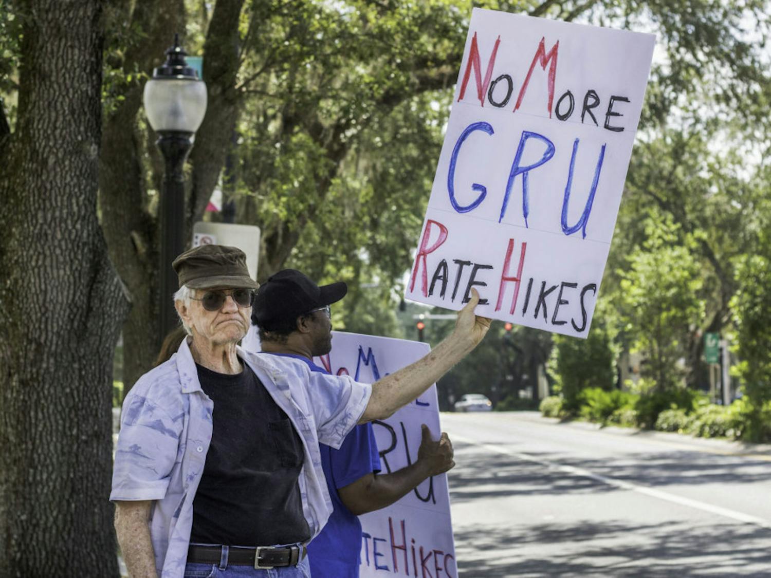 Harold Saive, 75, holds up a protest sign while Jason Davis, 46, stands behind him noon Thursday along University Avenue outside of City Hall. Saive said he believes that most people support the cause but are too timid to protest in person. “For every person who shows up here there’s a thousand behind them who agree,” Saive said.