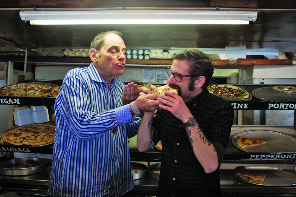 Steve Solomon, the owner of Leonardo's Pizza By The Slice, passes a pizza, which represents the business, to Brian Johnson, an employee of more than 20 years, on Thursday afternoon at Leonardo's Pizza By The Slice. "I'm nervous but ready and excited," Johnson said about taking over the business.