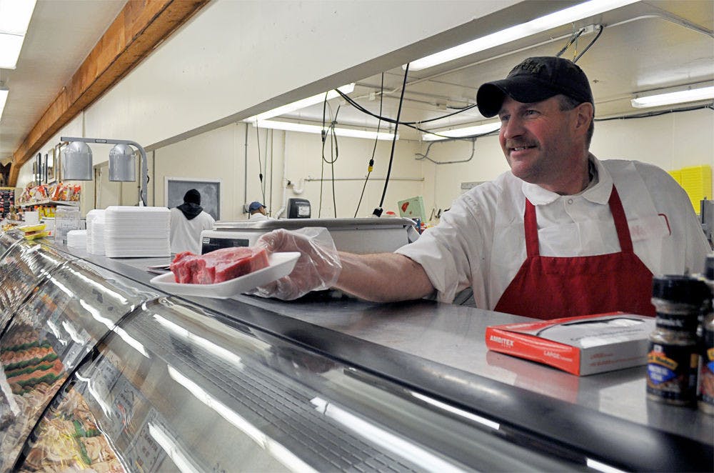 <p>David Farrell, 48, displays a steak to a Ward's Supermarket customer on Tuesday.</p>