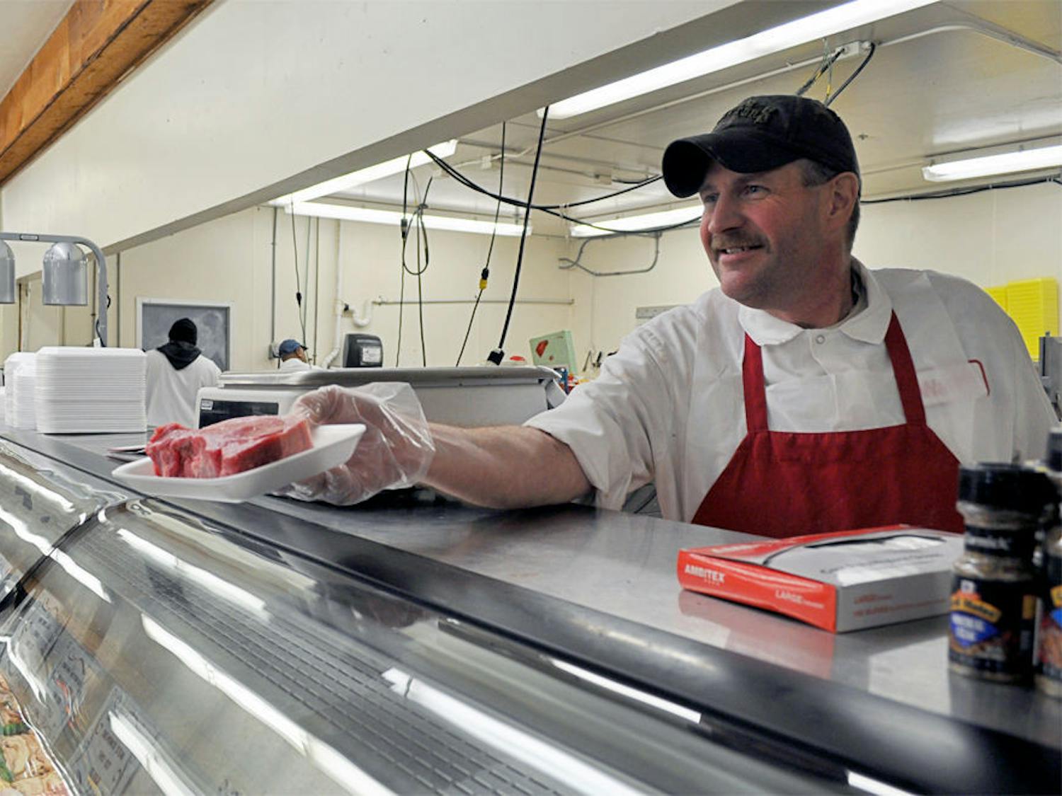 David Farrell, 48, displays a steak to a Ward's Supermarket customer on Tuesday.