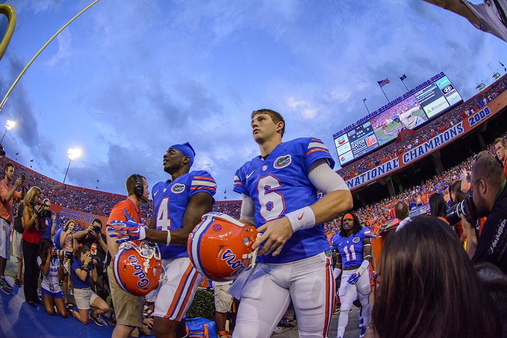 <p>Game capatins Andre Debose (4), Jeff Driskel (6) and Neiron Ball (11) walk out the players tunnel prior to kickoff between UF and UK on Sept. 15, 2014 evening in Ben Hill Griffin Stadium.</p>