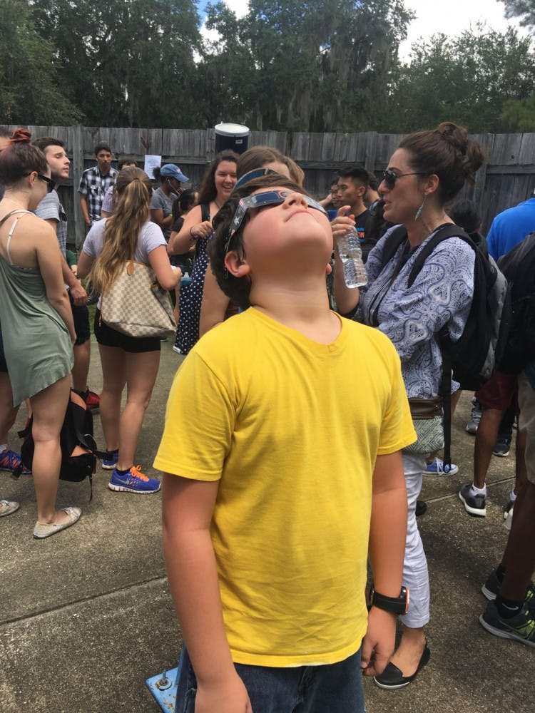 Nine-year-old Ian Sousa looks up at the eclipse with solar eclipse glasses. He was one of thousands who attended a viewing at&nbsp;UF Campus Teaching Observatory.