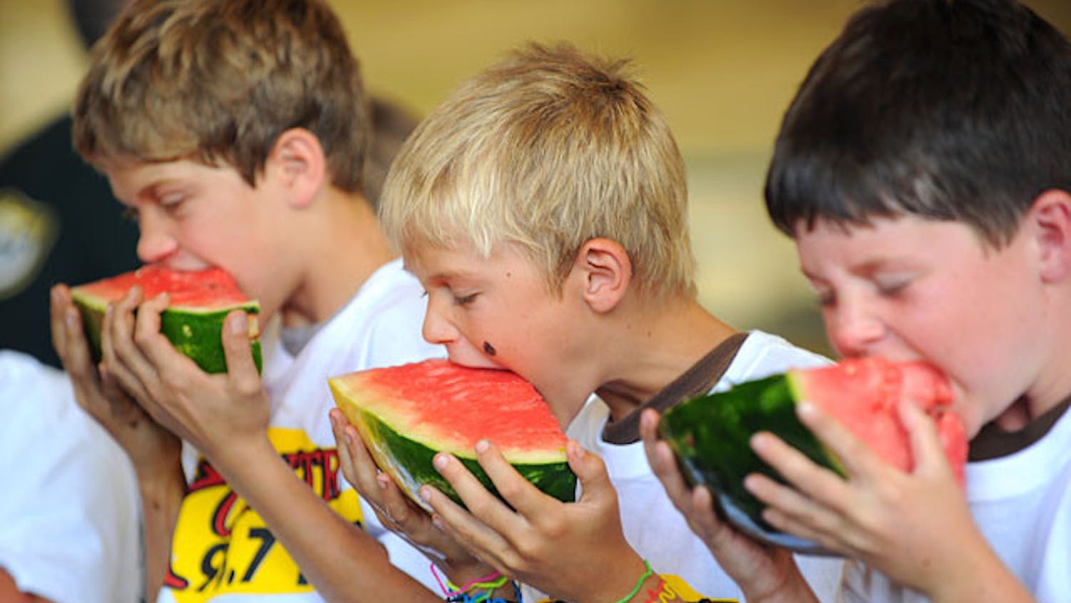 Zion Barber, left, Jacob Musselwhite and Colton Crane, right, sink their teeth into pieces of watermelon during the watermelon-eating contest at the 65th annual Newberry Watermelon Festival at the Canterbury Equestrian Showplace in 2010.