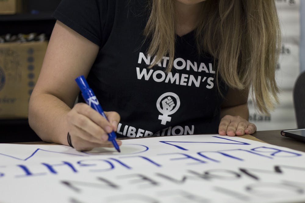 Alia DeLong, a UF doctoral student and member of the National Women’s Liberation, works on a sign that reads “Protect Women, Blue Lights Now” at the NWL sign-making event on the evening of Sept. 10.  “The reason the National Women’s Liberation is passionate about this is because we know that the culture associated with fraternities also happens to be associated with sexual assault,” DeLong said. “Knowing that women lack that resource is why we’re concerned.”