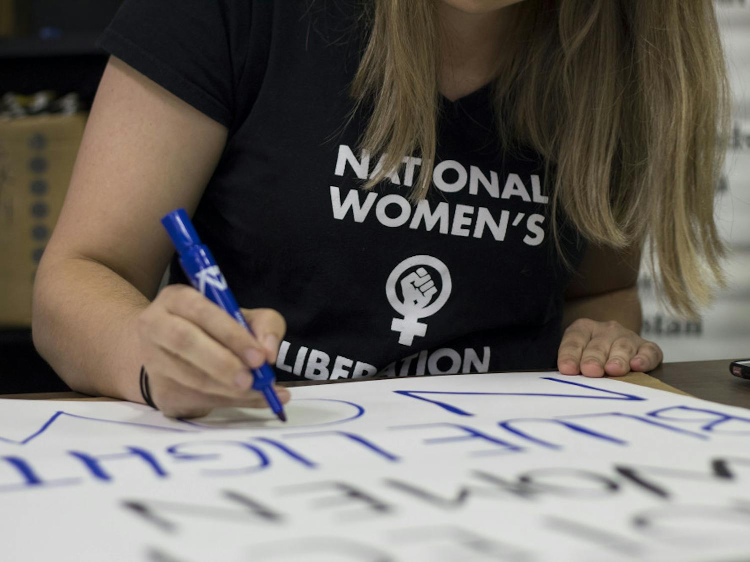 Alia DeLong, a UF doctoral student and member of the National Women’s Liberation, works on a sign that reads “Protect Women, Blue Lights Now” at the NWL sign-making event on the evening of Sept. 10. “The reason the National Women’s Liberation is passionate about this is because we know that the culture associated with fraternities also happens to be associated with sexual assault,” DeLong said. “Knowing that women lack that resource is why we’re concerned.”