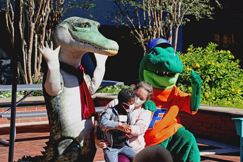 <p>A child poses with Lyle the Crocodile and Albert the Gator at a UF Health Shands Hospital event where President Kent Fuchs and his wife read &quot;Lyle, Lyle, Crocodile&quot; to a group of children Tuesday, Oct. 4, 2022.</p>