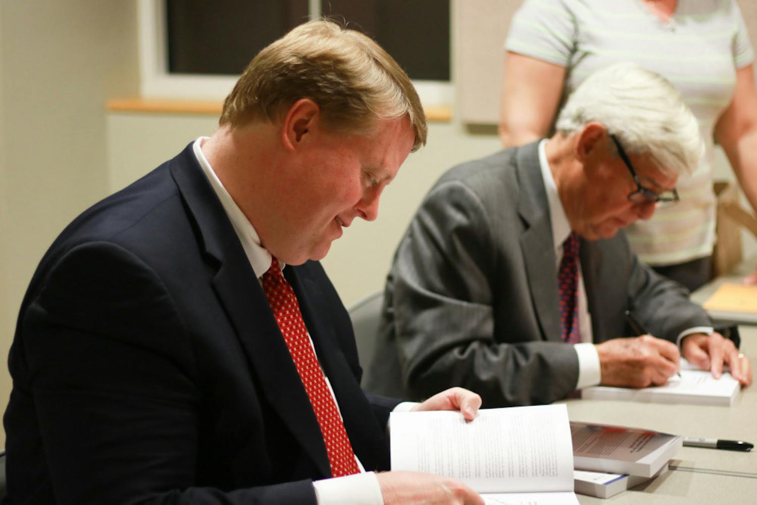 Chris Hand, a UF alumnus and attorney, signs copies of the second edition of “America, the Owner’s Manual: Making Government Work For You,” with the book’s co-author, former Florida Gov. Bob Graham.