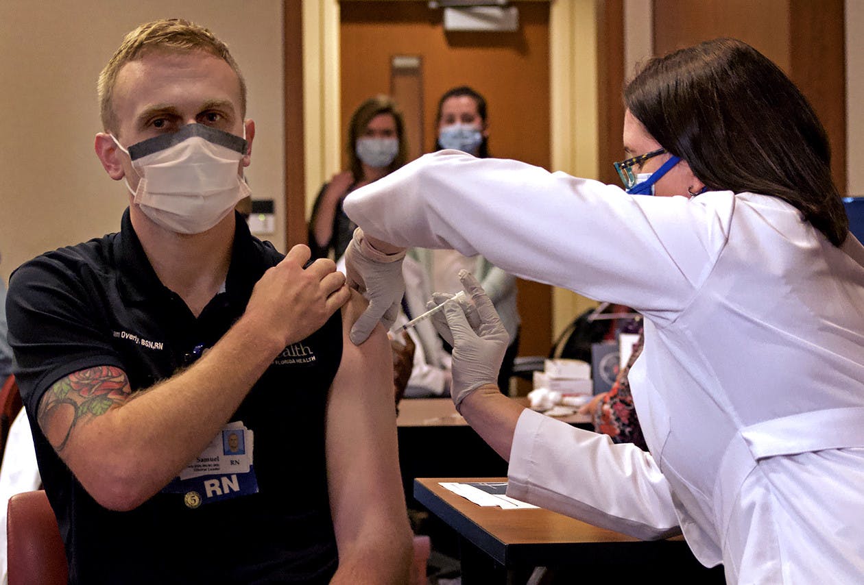 Samuel Overly, a UF Health clinical leader, is the first to get the Pfizer-BioNTech COVID-19 vaccine at UF Health Shands Cancer Hospital on Dec. 16, 2020. Suzy Wise administered the anticipated shot.