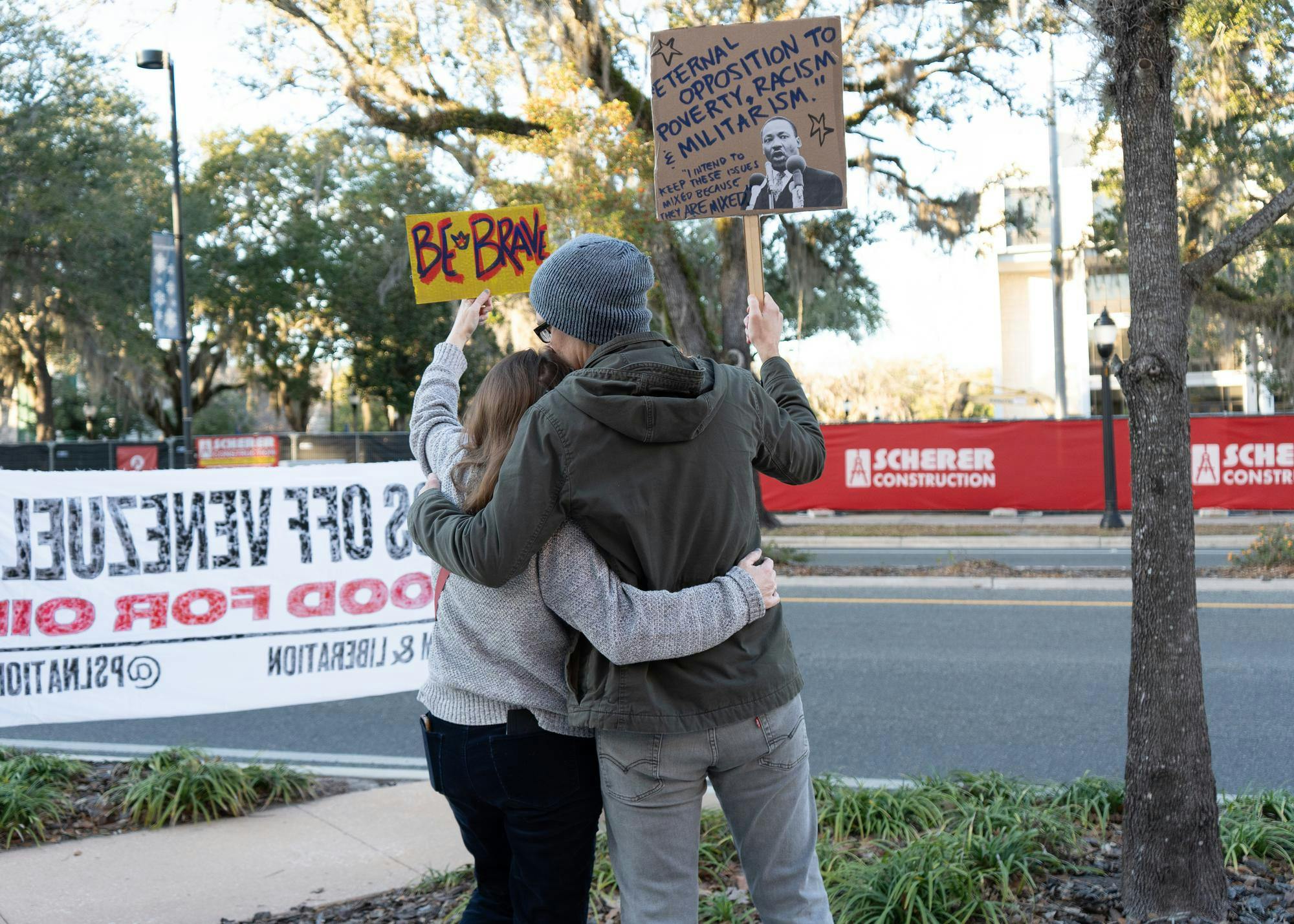 Marthe Walters and Eric Lemstrom embrace while holding up signs at the ICE protest in Gainesville, Fla., Tuesday, Jan. 20, 2026.