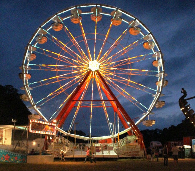 Patrons walk in front of a Ferris wheel Monday evening at the Alachua County Fair, held at the Alachua County Fairgrounds, 3100 NE 39th Ave. The fair runs through Saturday.