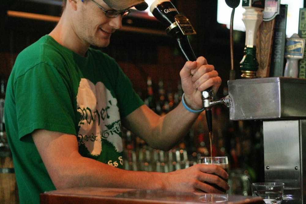 <p>Nick Brigandi, a 28-year-old employee at Mother's Pub &amp; Grill, pours a beer on Wednesday afternoon. Brigandi and other employees are preparing for all the business on St. Patrick's Day by wearing shirts from last year's festivities.</p>