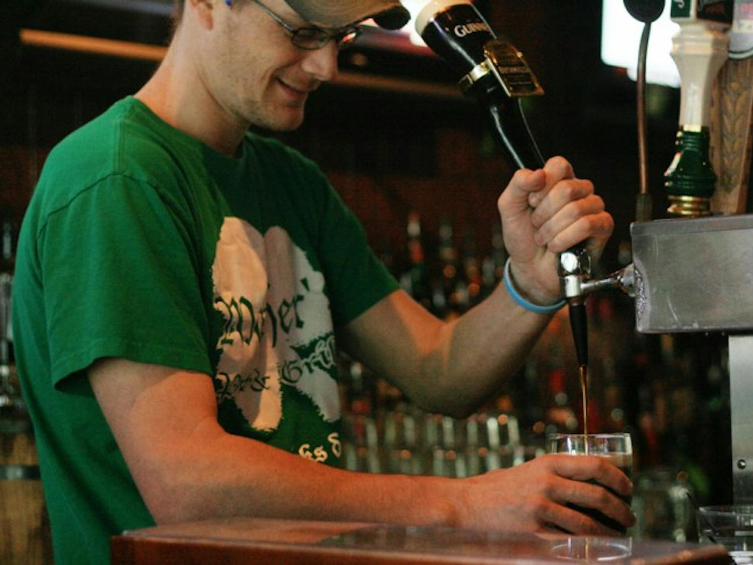 Nick Brigandi, a 28-year-old employee at Mother's Pub &amp; Grill, pours a beer on Wednesday afternoon. Brigandi and other employees are preparing for all the business on St. Patrick's Day by wearing shirts from last year's festivities.