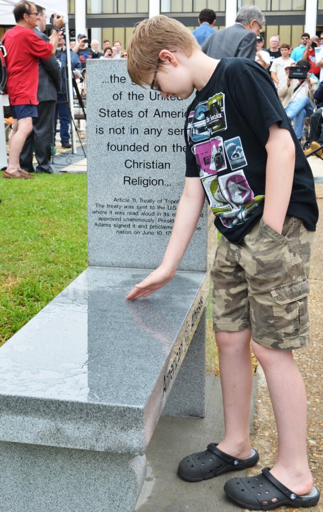 Chandler Allen, 10, of Orlando, was the first to sit on the newly revealed atheist monument outside the Bradford County Courthouse. 