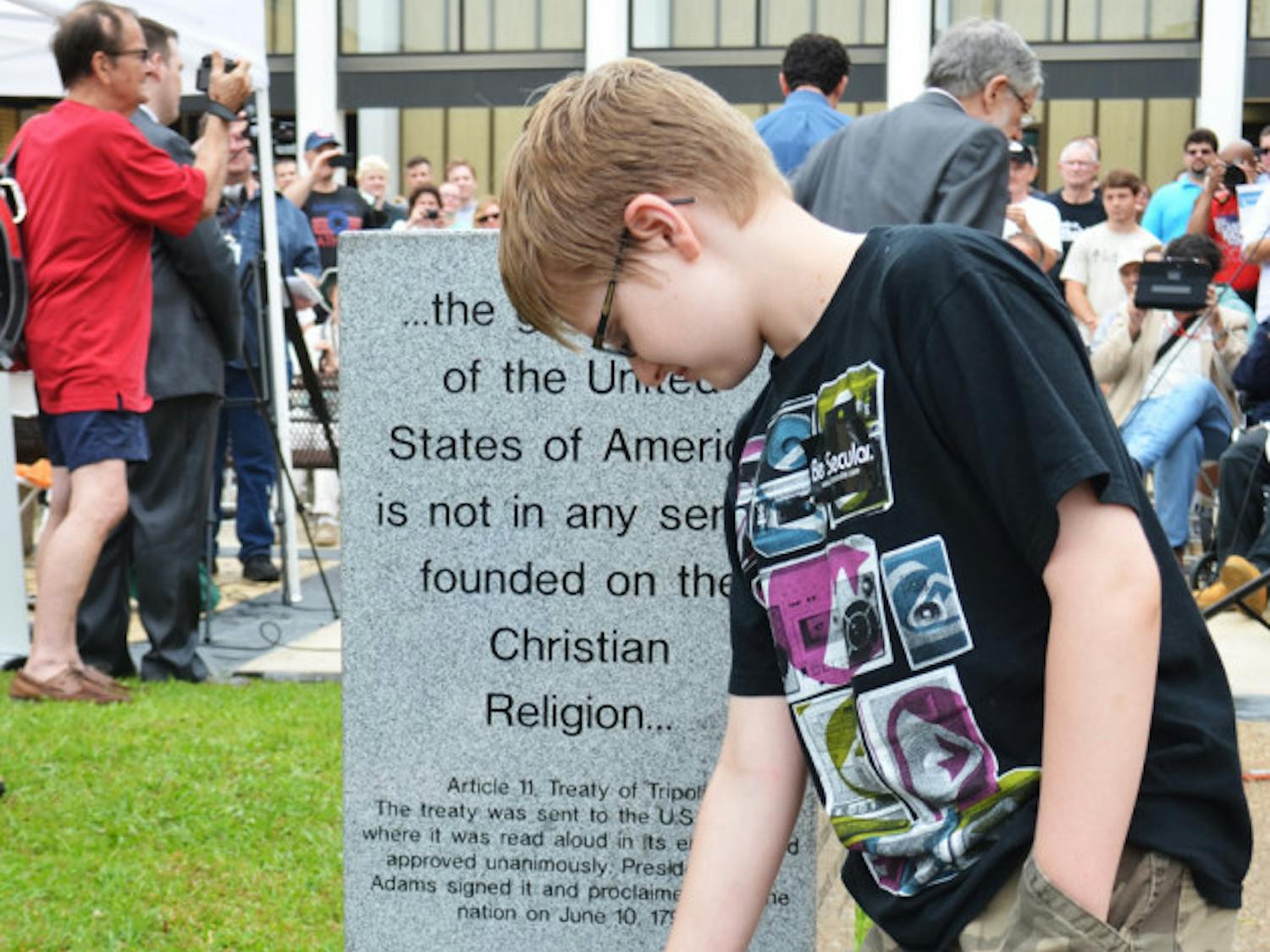 Chandler Allen, 10, of Orlando, was the first to sit on the newly revealed atheist monument outside the Bradford County Courthouse.