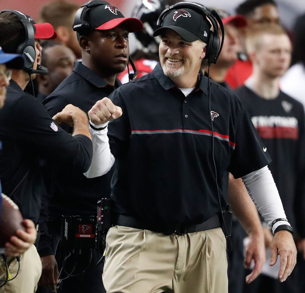 Atlanta Falcons head coach Dan Quinn fist bumps a coach after the Carolina Panthers were stopped during the first half of an NFL football game, Sunday, Oct. 2, 2016, in Atlanta. (AP Photo/John Bazemore)