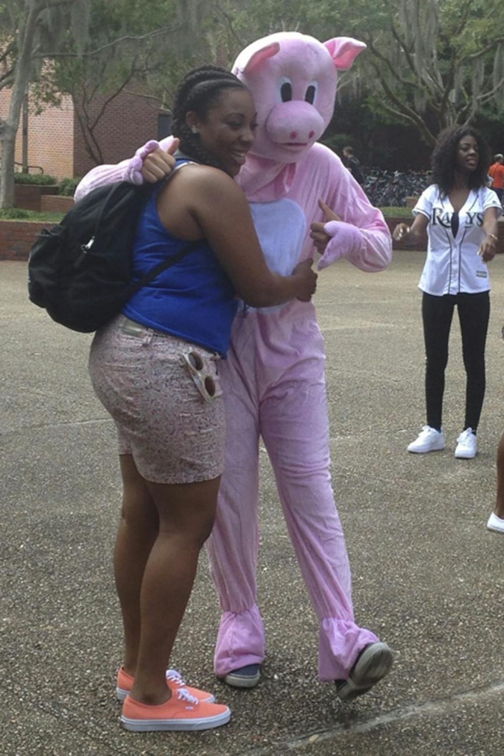 <p>Kennita Whitehead (left), a 19-year-old UF nursing sophomore, hugs Manny Rutinel, a 20-year-old microbiology and economics senior, who dressed in a pig costume for Hug a Vegan Day on Turlington Plaza on Sept. 25, 2015. Student Animal Alliance hosted the event to raise awareness for animal rights.</p>