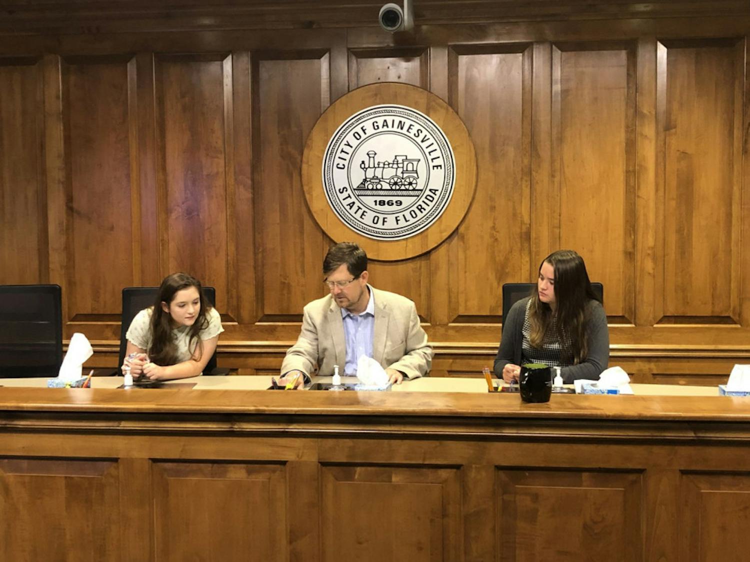 Mayor Lauren Poe (middle) allowed Keelyn Fife (left) and Alissa Humphrey (right) to sit in the city commission chairs while watching their peers’ presentation.