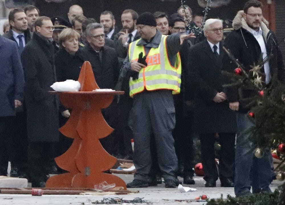 German Chancellor Angela Merkel, third from left, Interior Minister Thomas de Maiziere, fourth from left, and German Foreign Minister Frank-Walter Steinmeier, second from right, visit the site of the attack in Berlin, Germany, Tuesday, Dec. 20, 2016, the day after a truck ran into a crowded Christmas market and killed several people. 
