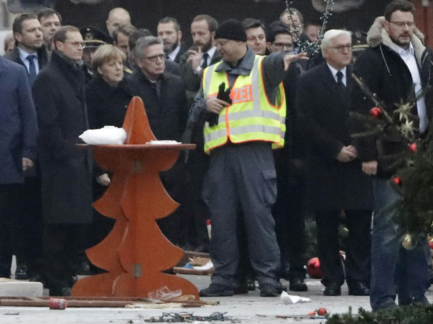 German Chancellor Angela Merkel, third from left, Interior Minister Thomas de Maiziere, fourth from left, and German Foreign Minister Frank-Walter Steinmeier, second from right, visit the site of the attack in Berlin, Germany, Tuesday, Dec. 20, 2016, the day after a truck ran into a crowded Christmas market and killed several people. 