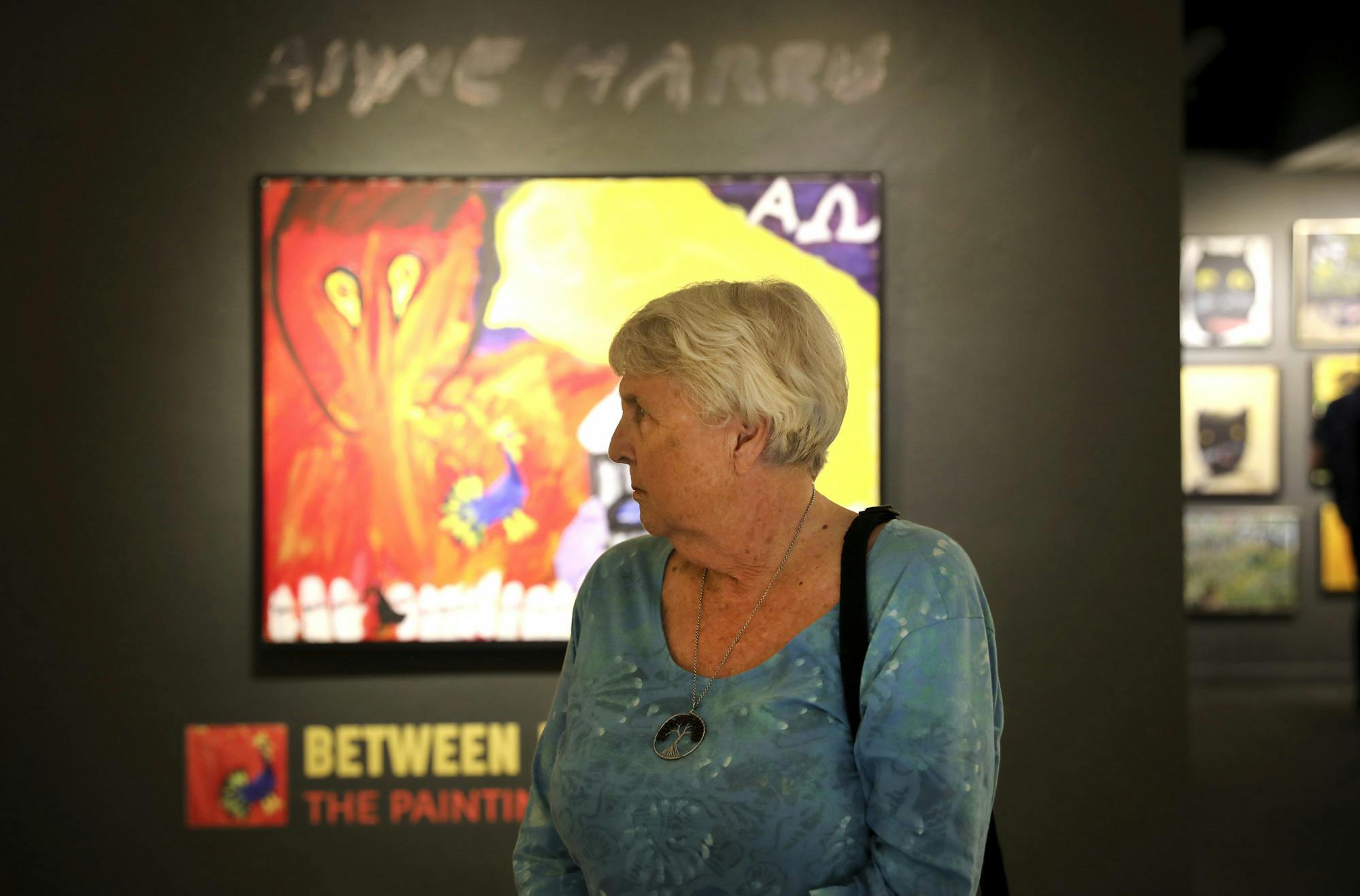 Nancy Parkinson, 80, a Gainesville resident, stands in front of artwork at the "Between Heaven and Earth" exhibit at the Historic Thomas Center on Thursday, June 17, 2021. 
