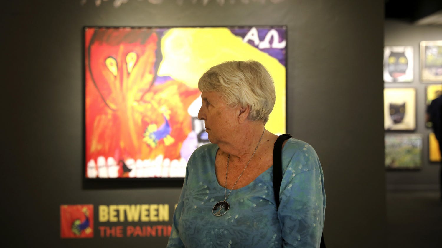 Nancy Parkinson, 80, a Gainesville resident, stands in front of artwork at the "Between Heaven and Earth" exhibit at the Historic Thomas Center on Thursday, June 17, 2021. 