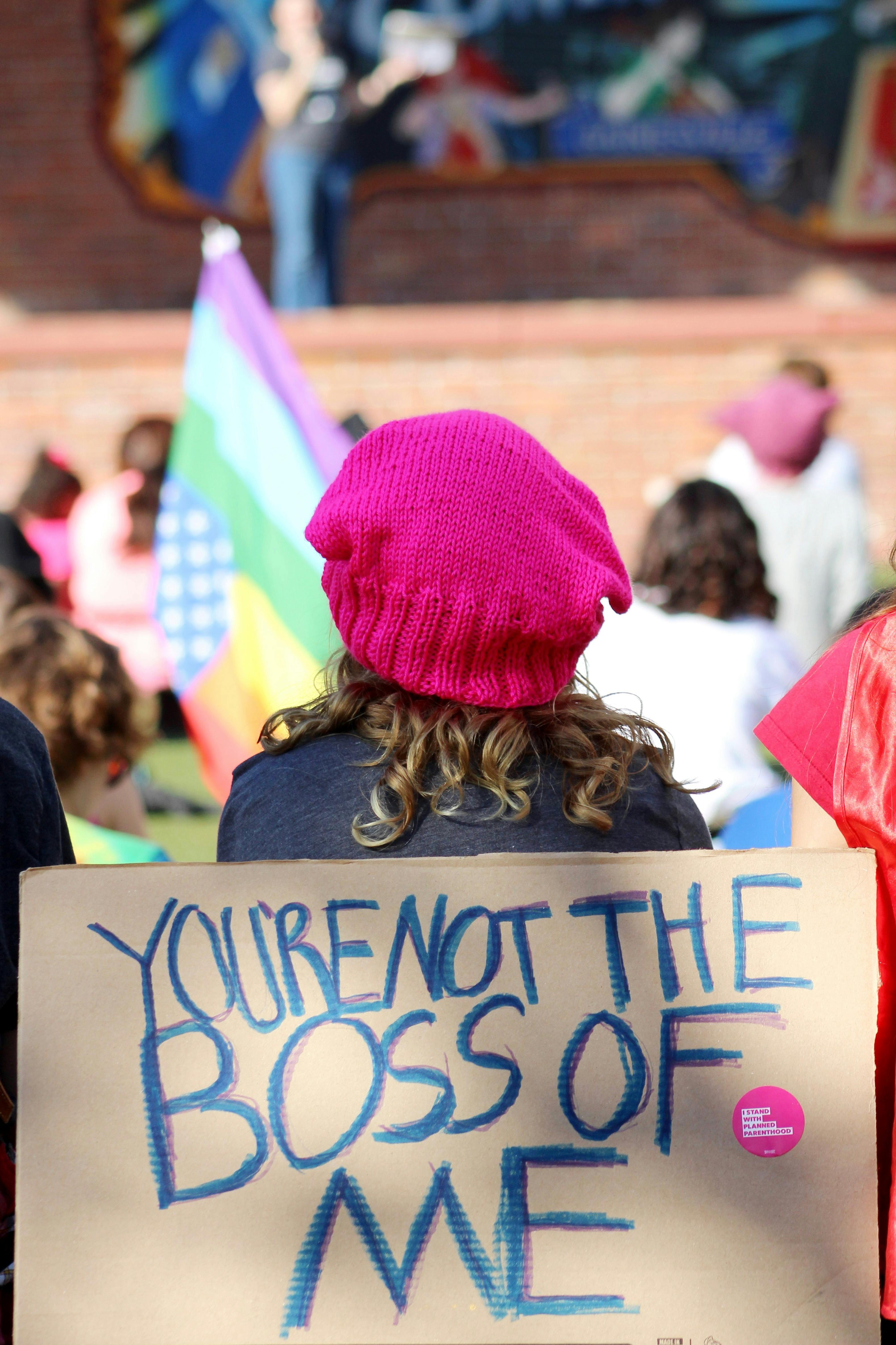 A protester wearing the signature pink knit hat to the Women's Resistance movement sits among a crowd of protesters gathered on Bo Diddley Community Plaza to listen to speakers before marching down University Avenue to raise support for female involvement in the American political process. Donations were collected for areas affected by the 2017 hurricane season.
