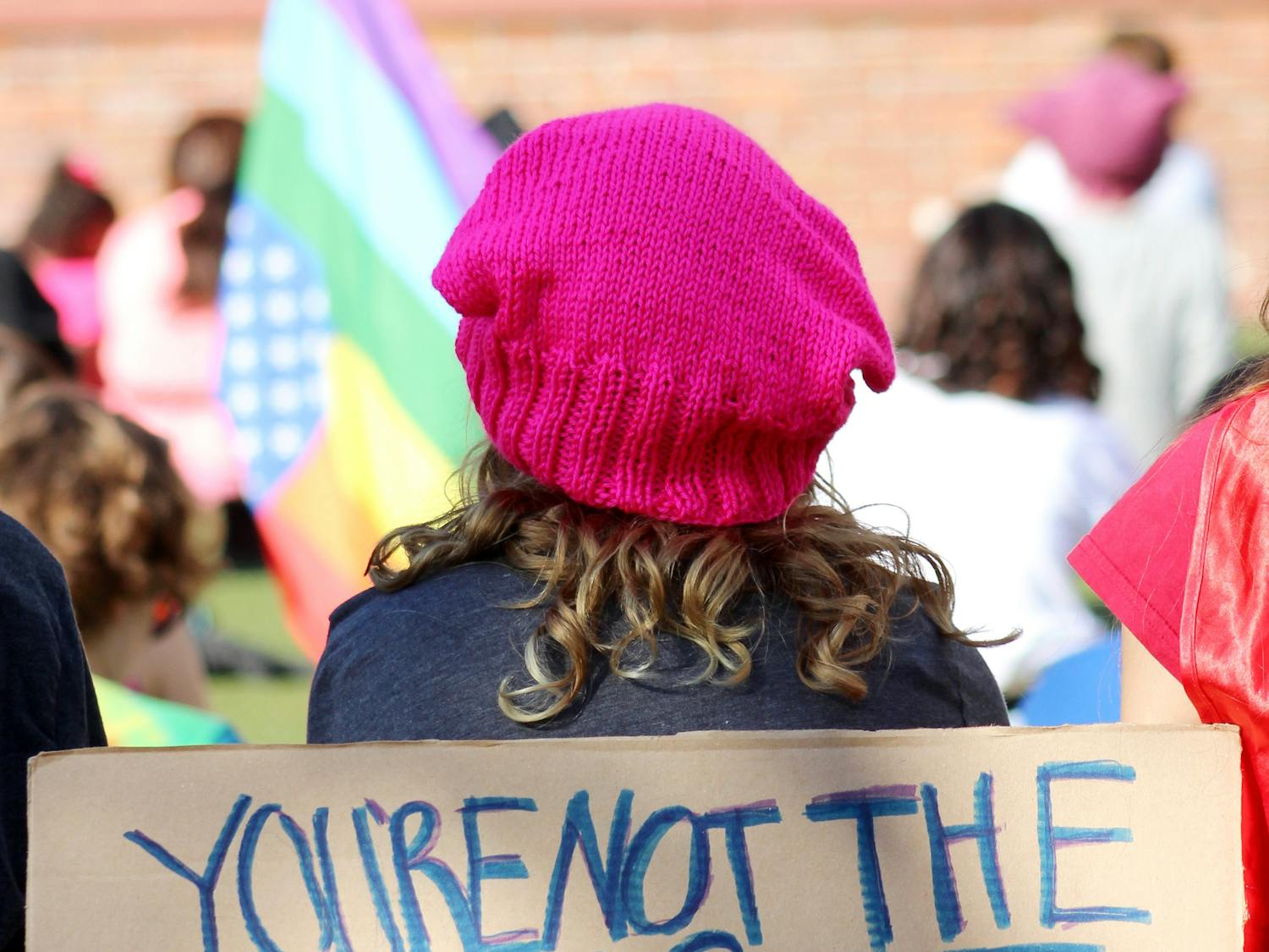 A protester wearing the signature pink knit hat to the Women's Resistance movement sits among a crowd of protesters gathered on Bo Diddley Community Plaza to listen to speakers before marching down University Avenue to raise support for female involvement in the American political process. Donations were collected for areas affected by the 2017 hurricane season.