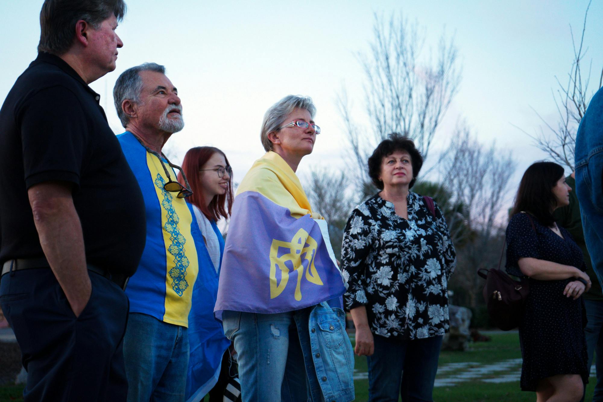 Natalia Pluzhnyk, 47, wrapped in a Ukrainian flag stands in the crowd of Ukrainian Gainesville residents at Depot Park Friday, Feb. 24, 2023.