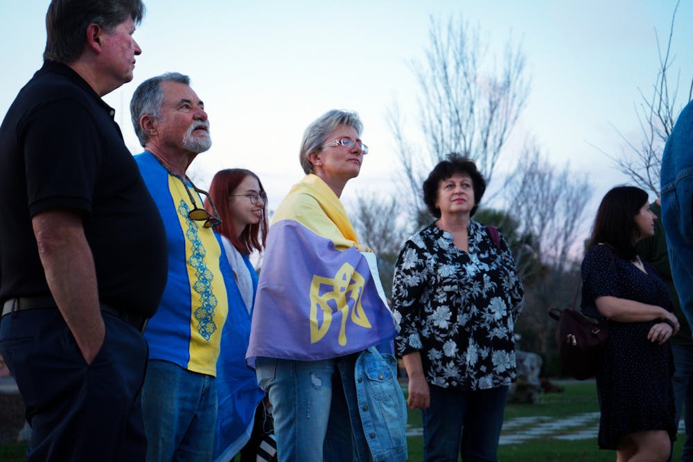 <p>Natalia Pluzhnyk, 47, wrapped in a Ukrainian flag stands in the crowd of Ukrainian Gainesville residents at Depot Park Friday, Feb. 24, 2023.</p>
