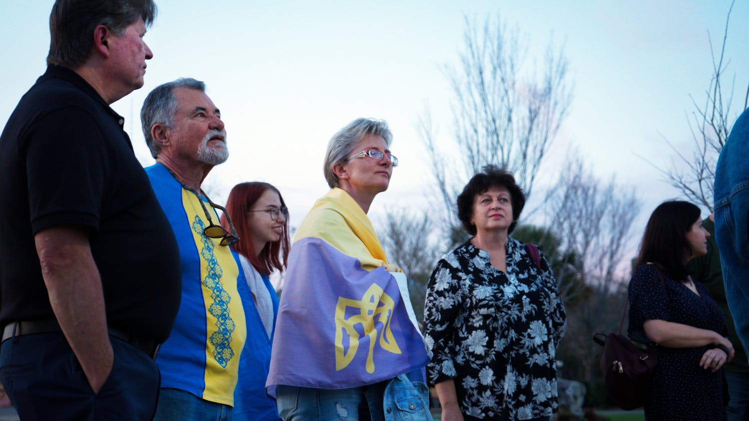 Natalia Pluzhnyk, 47, wrapped in a Ukrainian flag stands in the crowd of Ukrainian Gainesville residents at Depot Park Friday, Feb. 24, 2023.