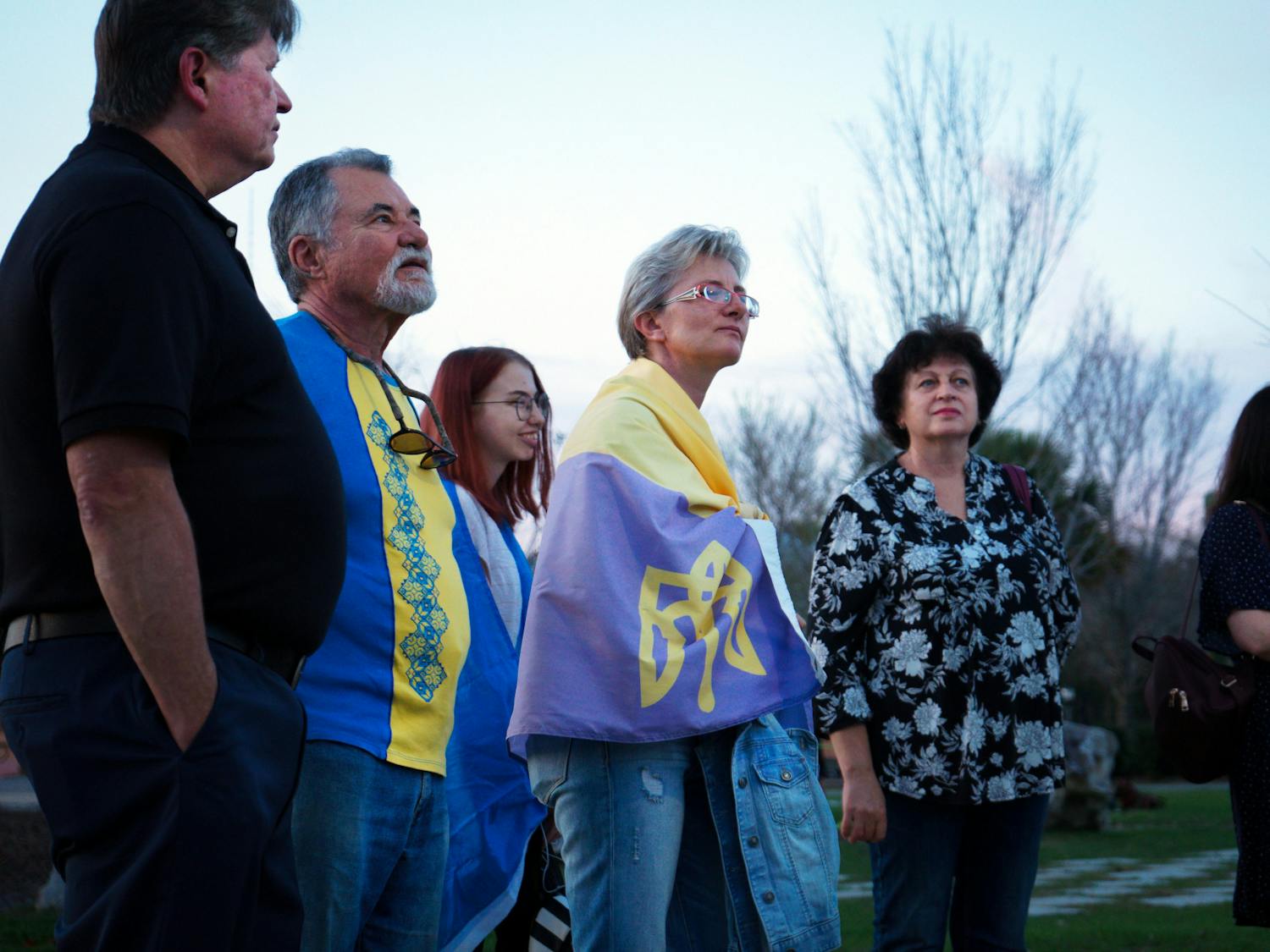 Natalia Pluzhnyk, 47, wrapped in a Ukrainian flag stands in the crowd of Ukrainian Gainesville residents at Depot Park Friday, Feb. 24, 2023.