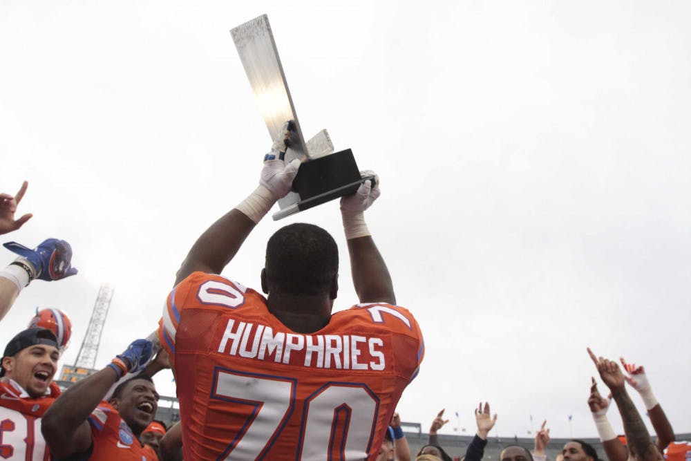 <p>D.J. Humphries holds up the Birmingham Bowl trophy following Florida's 28-20 win against East Carolina on Saturday at Legion Field.</p>