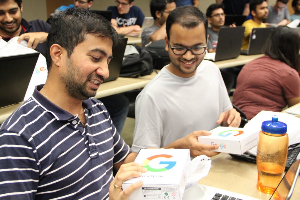 (From left to right) Master's computer science students, 35-year-old Pradeep Rajan and 25-year-old Harshit Vijayvargia, excitedly open goodie bags from Google. Rajan and Vijayvargia were some of the lucky few who ran up to get these bags.